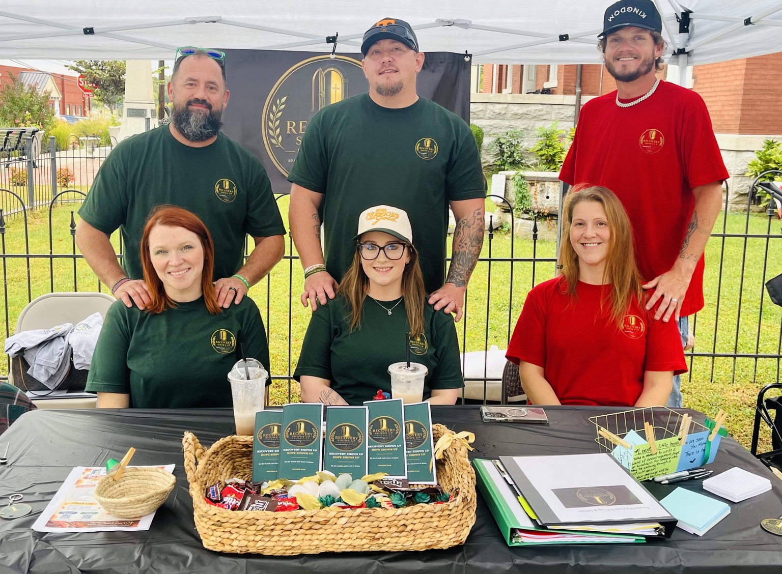 Six people wearing foundation shirts gathered at the Recovery Shows Up outreach table